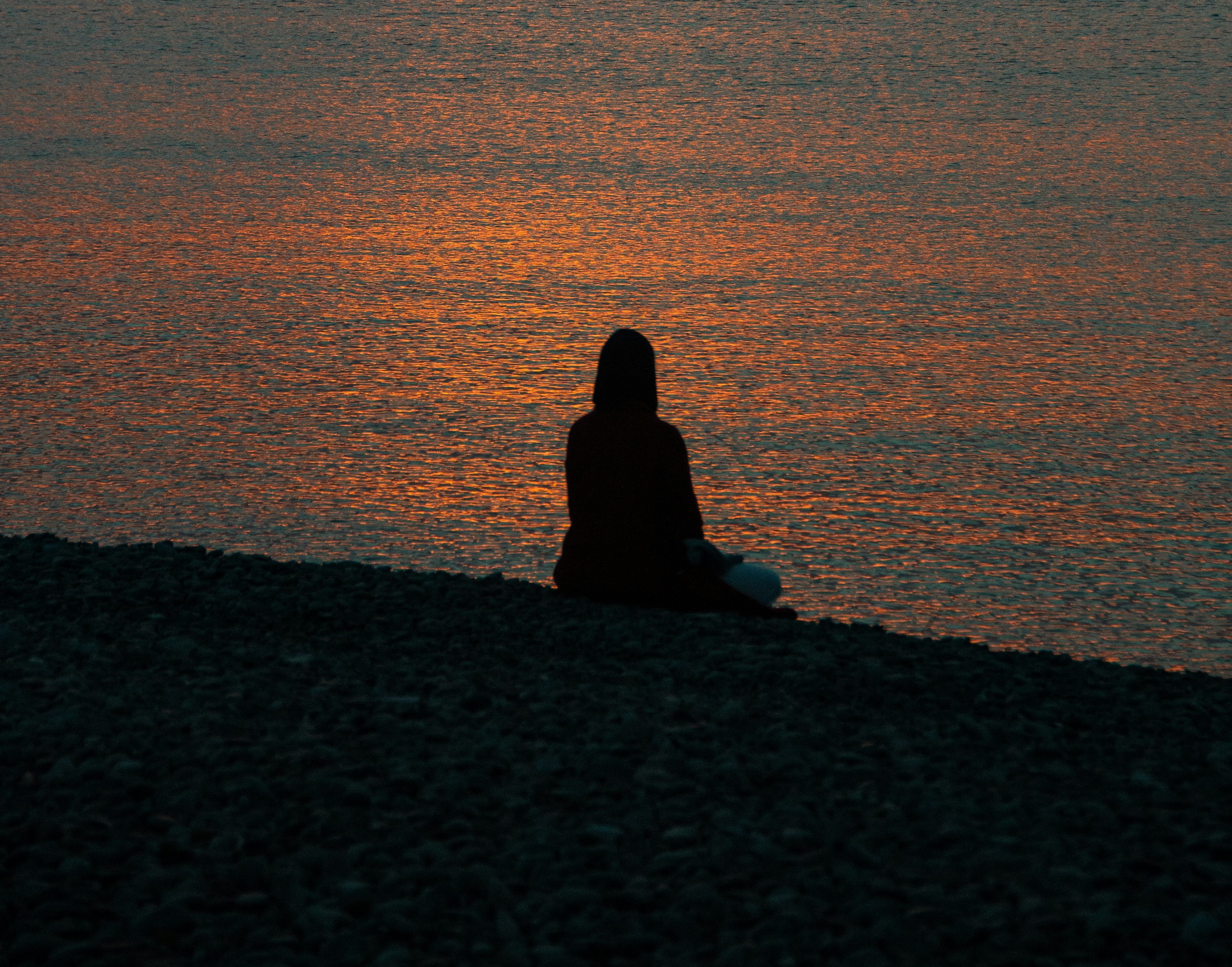 Людина на березі водойми під час заходу сонця